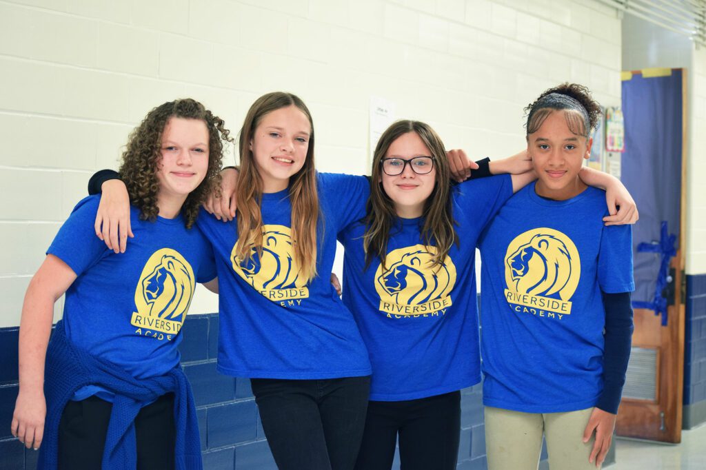 Group of smiling students with their arms around each other