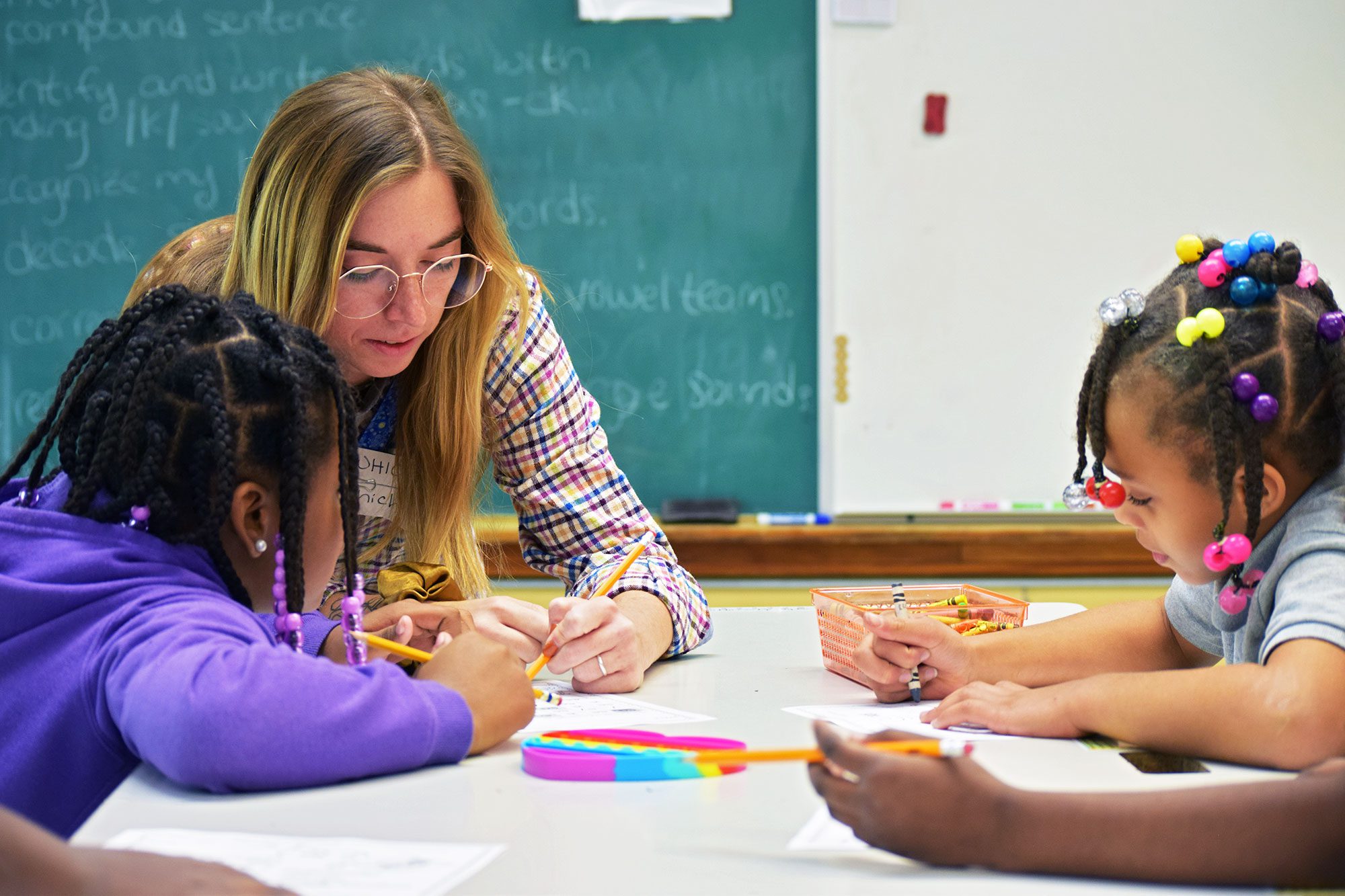 Teacher helping elementary students with their activity in a classroom.