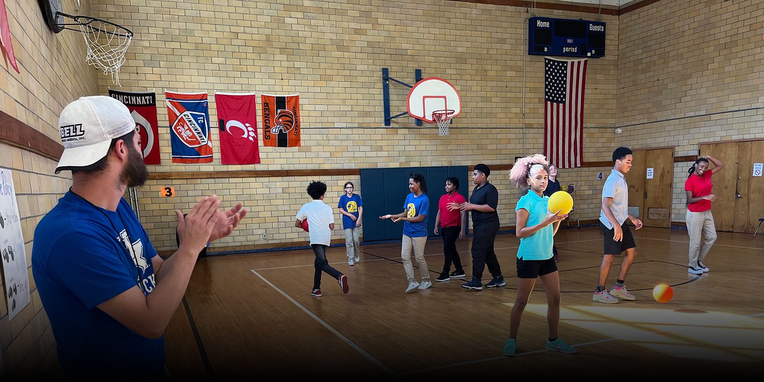 A Teacher and group of students playing on the basketball court
